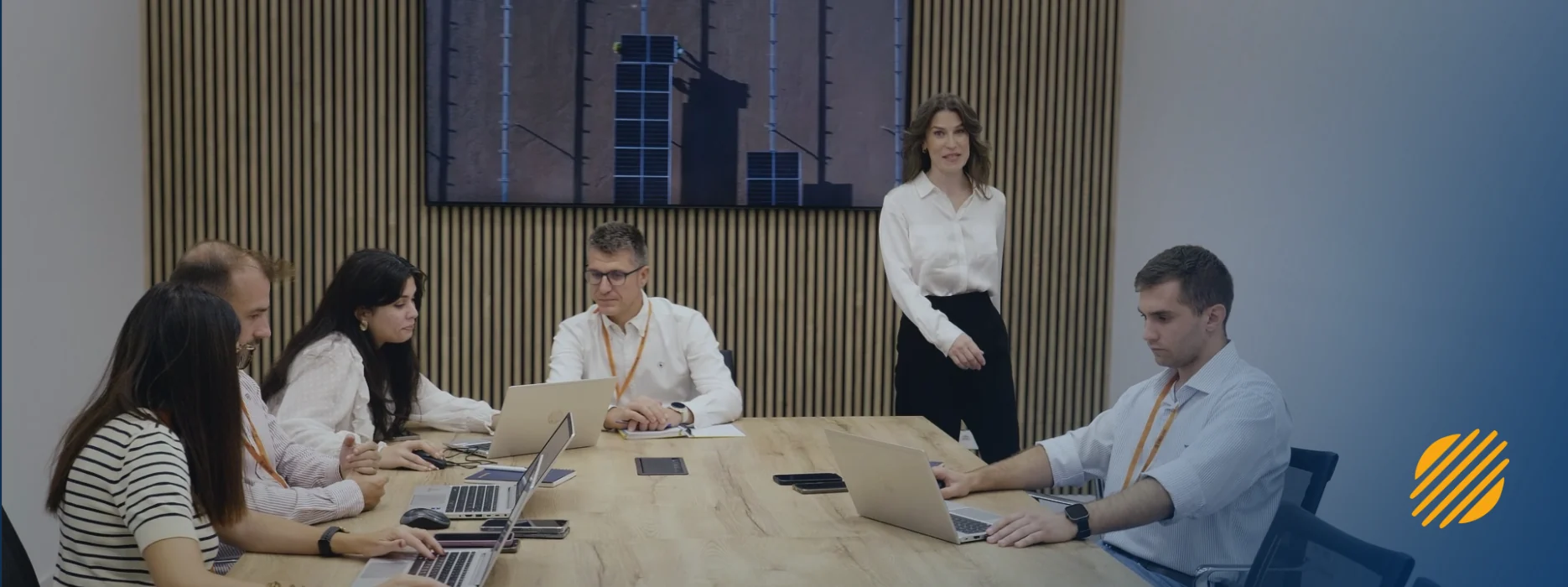 Equipo de Enerland reunido alrededor de una mesa con ordenadores portátiles y el símbolo de la marca a la derecha